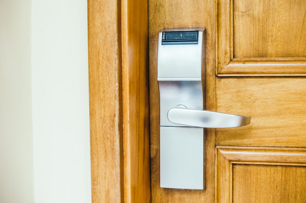 Modern keyless door lock with an illuminated keypad on a wooden door.