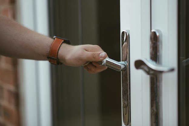 A person opening a door handle showcasing the importance of secure entry points in residential security.