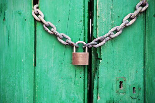 An old wooden door with a padlock representing outdated home security needing lock upgrades.