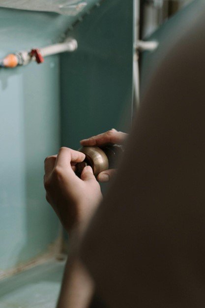 Person repairing a brown doorknob while opening or securing a door, symbolizing poor home security.
