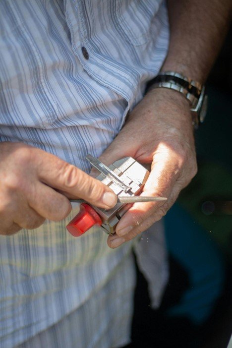 Close-up of a locksmith filing a car key blade for accurate cutting and smooth function.