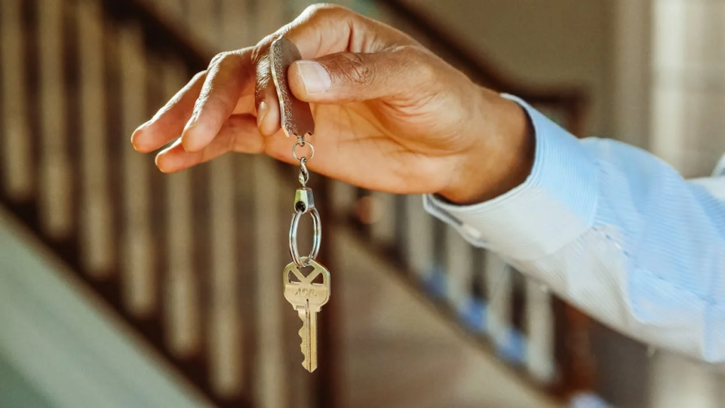 person holding a single house key on a keychain, symbolizing rental access.
