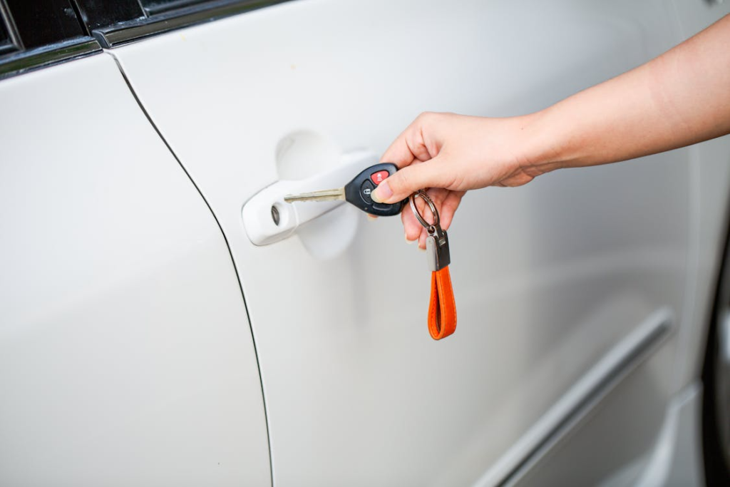 Hand inserting a car key into a white vehicle door by a car locksmith in Las Vegas.