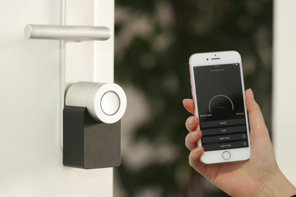 Person controlling a smart lock via smartphone app to enhance workplace security.