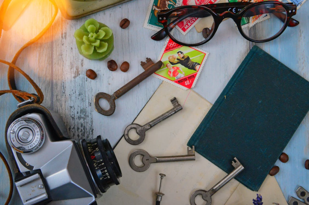 4 keys next to a notebook and glasses, and a camera 